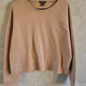 Beige tröja från Amisu - Säljer en stilren beige tröja från Amisu. Tröjan har en rund halsringning och långa ärmar, perfekt för en avslappnad look. Materialet är mjukt och bekvämt, vilket gör den idealisk för vardagsbruk.