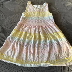 Flerfärgad ärmlös klänning - Charmig ärmlös klänning med ett färgglatt mönster i rosa, gult och blått. Klänningen har en rund hals och ett luftigt fall, perfekt för varma dagar.