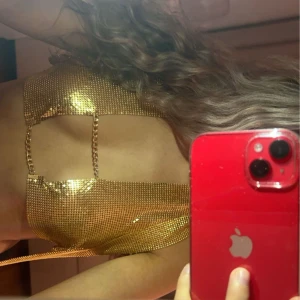 Glittrig guld top - Snygg glittrig guld topp med knytband. Perfekt för att glänsa på en fest eller event. Den har en trendig design som verkligen fångar ögat.