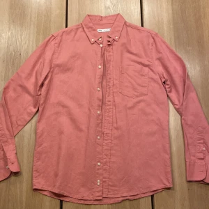 Säljer en jättefin rosa herr linneskjorta från Zara 🩷 - Säljer en stilren rosa linneskjorta från Zara i herrstorlek M. Säljer åt min bror👍🏻Skjortan har långa ärmar och knappar framtill samt en bröstficka.👍🏻Perfekt för en avslappnad men ändå uppklädd look. Perfekt till våren/sommaren.👌🏻Sparsamt andvänd, inga håll eller nått. Skriv om funderingar 💭priset kan diskuteras och lämna gärna omdöme om köpt😊