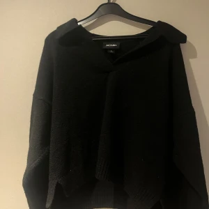 Svart tröja från Monki - Snygg svart tröja från Monki med en avslappnad passform. Tröjan har långa ärmar och en bred krage som ger en stilren look. Perfekt för kyligare dagar.