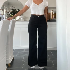 Svarta byxor från H&M - Snygga svarta byxor från H&M med hög midja och raka utsvänga ben . Tillverkade i ett bekvämt bomullsmaterial. Midja 32 cm. innerben 72 cm. 