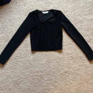 Svart glittrig topp från H&M - Snygg svart glittrig topp från H&M med långärmad design. Perfekt för att lägga till lite glitter i garderoben. Toppen har en elegant passform och är idealisk för speciella tillfällen. Storlek 158/164. Använd ett fåtal gånger 💗