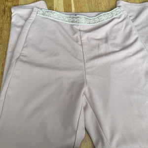 Rosa  byxor med broderad midja - Snygga rosa byxor med en unik broderad detalj vid midjan. Perfekta för en stilren look med en touch av elegans.