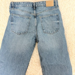 Blå jeans från Pull&Bear - Snygga blå jeans från Pull&Bear med klassisk femficksdesign och knappgylf. Perfekta för en avslappnad stil med en rak passform och bekväm midja.