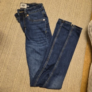 Blå jeans från 157 - Snygga blå jeans från 157 med klassisk design. De har en rak passform och är perfekta för en avslappnad stil. Jeansen har fem fickor och en knappgylf.
