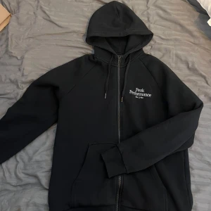 Svart hoodie från Peak Performance - Svart zip-hoodie från Peak Performance i storlek L. Hoodien är i mycket bra skick och sparsamt använd.