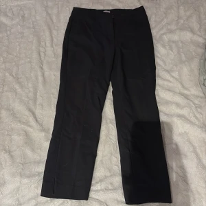 Svarta kostymbyxor med slits - Snygga svarta kostymbyxor med en stilren design. Byxorna har en diskret slits vid benslutet och en klassisk passform. Perfekta för en elegant look. Jag är 160 cm lång och dom slutar ungefär vid fotknölen på mej!