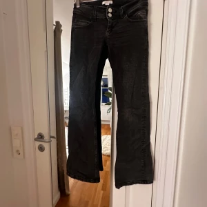 Svarta bootcut jeans - Snygga svarta bootcut jeans med låg midja och dubbla knappar fram. Perfekta för en avslappnad stil med en touch av retro. Passar bra till både sneakers och klackar.