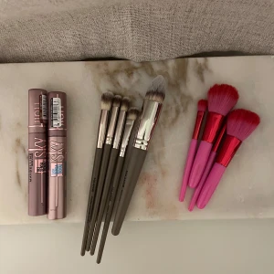 Nya maybelline sky high mascaror och sminkborstar - 2 st helt oanvända Maybelline Lash sensational Sky High Mascaror i färgen brown och black. 5 st helt oanvända sminkborstar från mange. 4 st lätt rosa använda sminkborstar.