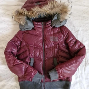 Vinröd GUESS-jacka - Säljer denna fantastiska pufferjacka från GUESS 🎀 I fint skick! Vinröd med grå muddar, pälsluva och markerad midja. Storlek M på lappen men passar som en S. Köpt på Vinted, måste tyvärr sälja då den är för liten för mig!   Pris är självklart förhandlingsbart 😊 Hör gärna av er vid frågor och glöm inte att kolla in garderoben för fler liknande plagg! 💕