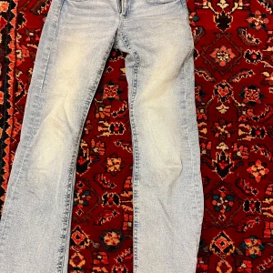 Ljusblå jeans från Gina Tricot - Snygga ljusblå jeans från Gina Tricot med klassisk femficksdesign och knappdetaljer på bakfickorna. Perfekta för en avslappnad stil. Köpte de för ca 6 månader sedan och de är knappt använda, inga defekter. Skriv för mer bilder eller frågor!