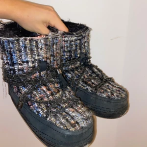 Flerfärgade boots från Inuikii - Säljer ett par unika flerfärgade boots från Inuikii med ett stickat mönster och kedjedetaljer. De har en robust sula och är perfekta för kalla dagar. Insidan är fodrad för extra värme.