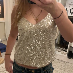 Glittrig guld topp - Säljer en glittrig guld topp med paljetter. Toppen är ärmlös och har en v-ringad design. Perfekt för festliga tillfällen! Använd en gång köpt för 400kr!❤️