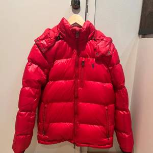 Snygg röd dunjacka från Ralph Lauren med dragkedja och huva. Jackan har långa ärmar och en liten logotyp på bröstet. Perfekt för kalla dagar. Köpt i Täby centrum på Thernlunds och är köpt för 6999 kr. Den är storlek S i vuxen storlek. DM mig om du är intresserad av att köpa! Den är bara använd förra vinter och är som i ny skick, så väldigt ny.❤️Om ni vill ha mer bilder så kan jag skicka hur den ser ut på.