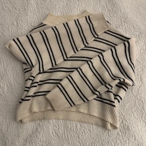 Randig stickad tröja från H&M - Säljer en snygg stickad tröja från H&M i beige med svarta ränder. Tröjan har en normal passform och långa ärmar, perfekt för höst och vinter. Den är mjuk och bekväm i storlek S. 