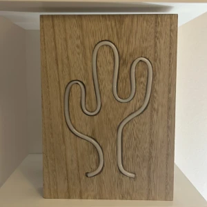 Trälampa med kaktusmotiv - Snygg trälampa med ett utskuret kaktusmotiv som lyser upp i grönt. Perfekt för att ge en unik touch till ditt rum. Lampan är batteridriven och har en naturlig träfinish.🌵🌴