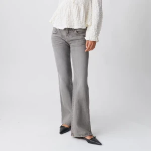 Snygga low waist grå bootcut jeans🩶 - Snygga grå bootcut jeans med hög midja och klassisk femficksdesign. Jeansen har en knappdetalj på bakfickan och är perfekta för en stilren look. Tillverkade i ett bekvämt denimtyg.