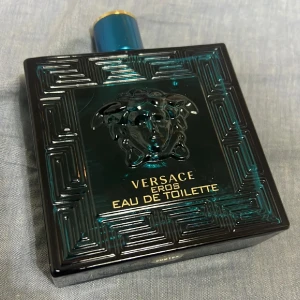 Versace Eros Eau de Toilette - Säljer en flaska Versace Eros Eau de Toilette. Flaskan är fyrkantig och mörkgrön med ett elegant mönster och Versaces ikoniska Medusa-logga i mitten. Korken är blå med en gyllene topp. Perfekt för den som vill ha en doft med karaktär. Pris kan diskuteras 