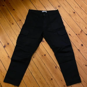 Svarta cargobyxor från Zara - Snygga svarta cargobyxor från Zara med flera praktiska fickor. Perfekta för en avslappnad och trendig stil. Byxorna har en klassisk passform och är tillverkade i ett slitstarkt material.