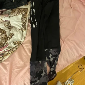 Svart långärmad tröja från Phelix Sports - Säljer svarta tränings-tights från Phelix Sports med texten 'WORK HARD FEEL STRNG' tryckt i vitt på framsidan. Byxorna har ett coolt camouflagemönster på benen. Perfekt för träning eller en aktiv vardag.Dom är använda men inga skador eller fläckar på😀