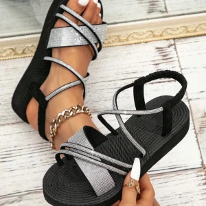 Svarta sandaler med glittriga remmar - Snygga svarta sandaler med glittriga remmar som korsar över foten. Perfekta för sommarens alla tillfällen. Sandalerna har en bekväm sula och en stilren design.