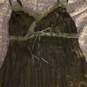 Svart satin topp med spetsdetaljer - Elegant svart topp i satin med vackra spetsdetaljer och knytband i midjan. Axelbandslös design som ger en sofistikerad look.