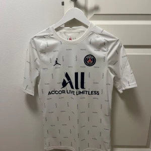 Vit PSG fotbollströja  - Snygg vit PSG fotbollströja från Jordan med korta ärmar. Säljer pågrund av att den har blivit för liten på mig. Pris går att diskuteras. Hör av er vid frågor. 