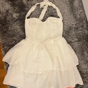 Vit klänning - Vit klänning med volang, perfekt som student klänning. Helt oanvänd med prislapp kvar. Storlek Xs men passar även S