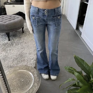 Blå bootcut jeans med knappar - Snygga blå bootcut/flare jeans med låg midja och dekorativa knappar på fickorna. Säljer då de är för stora. Inga synliga defekter💗