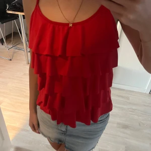 Röd volangtopp - Snygg röd topp med volanger. Aldrig använd och lappen är kvar. Köpt på missay! Kom privat vid fler frågor, kan gå ner i pris vid snabb affär!💓nypris 229kr, mitt pris 50