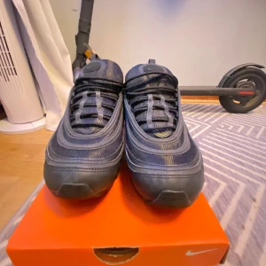 Svarta Nike Air Max sneakers - Nike Air Max 97 i färgen svart. Skorna har inte kommit till användning då dem är för små. Har använts 1 gång tidigare då det finns lite grus på under sulan. Annars är skorna i perfekt skcik. Mycket billigare alternativ än att köpa nyare par.                 Original box medföljer samt kvitto på sista sliden