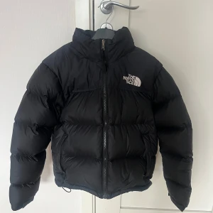 The North Face jacka - Säljer den populära svarta jackan från The North Face. Den är använd men i bra skick, den är dessutom tvättad och torktumlad👍🏻. Den har inga synliga defekter. Denna jacka har en inbyggd luva som övriga north face jackor. Jackan är både varm och tål vatten. Den är perfekt.