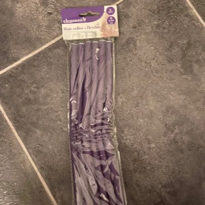 Lila flexibla hårspolar från Eleganza - Säljer ett paket med lila flexibla hårspolar från Eleganza. Perfekta för att skapa snygga lockar utan värme. De är lätta att använda och skonsamma mot håret. Paketet innehåller flera spolar i en praktisk förpackning. Perfekt för både kort och långt hår!