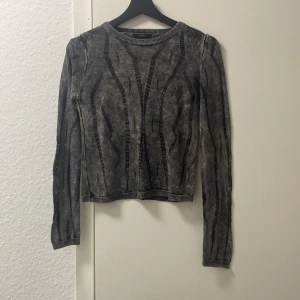 Grå tröja från Avrile - Säljer en snygg grå tröja från Avrile med ett unikt mönster. Tröjan är långärmad och har en cool, ribbad kant vid halsen. Perfekt för höst och vinter!