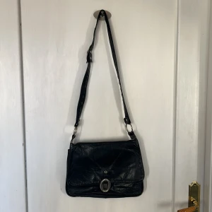 Axelväska - Fin svart väska med röd insida, tyvärr är spännet för att stänga trasigt men den är fortfarande i ganska bra kondition! Lite sliten på bandet