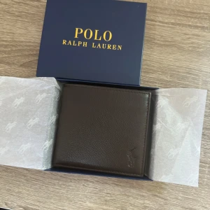 Polo Ralph Lauren Läder Plånbok *Helt Ny* - Polo Ralph Lauren plånbok i brunt läder. Helt ny.  Alla tags och låda medföljer. Äkthetsbevis finns Nypris: 995kr. 