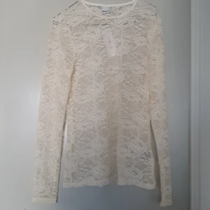 Vit spetsblus - Säljer en superfin vit spetsblus med långärmad design. Perfekt för både vardag och fest! Blusen är genomskinlig och har ett elegant mönster som ger en romantisk touch. Passar perfekt till ett par jeans eller en kjol för en chic look. Ny PRISLAPP kvar
