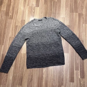 Grå stickad tröja - Grå stickad tröja med en cool ombre-effekt från ljusgrått till mörkgrått. Tröjan har långa ärmar och en rund halsringning, perfekt för höst och vinter. Oanvänd från LIVERGY i storlek M