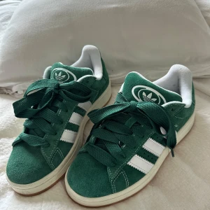 Adidas Campus Gröna - Säljer ett par Adidas Campus gröna i storlek 38 2/3. Knappt använda och främst använda inomhus. Väldigt fint skick, det enda är trycket inuti ena skon som blivit lite utslitet (se bild).  Pris kan diskuteras.