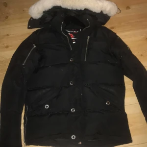 Svart dunjacka från Moose Knuckles - Säljer en snygg och varm svart dunjacka från Moose Knuckles. Jackan är i strlk M men lite problem med dragkedjan 