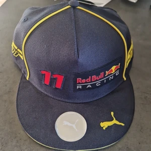 Redbull keps f1 - En äkta f1 keps som knappt är använd med sergio perez och nummer 11 på.