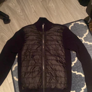 Svart jacka från Jimmy Sanders - Säljer en snygg svart jacka från Jimmy Sanders i storlek M. Jackan har en quiltad framsida med dragkedja och är tillverkad av 80% bomull och 20% polyester. Perfekt för höst och vår!