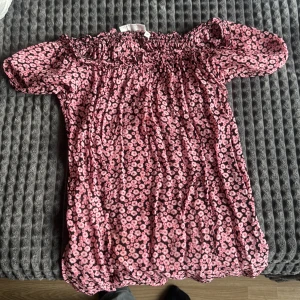 En blommig T-shirt  - Det är en en lite tunn T-shirt med små rosa blommor på 