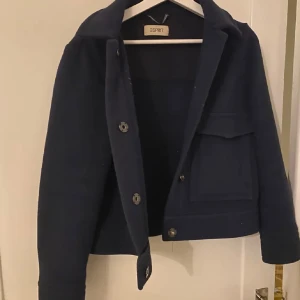 Mörkblå jacka från Esprit - Snygg mörkblå jacka från Esprit med knappar framtill. Jackan har en klassisk design med krage och långa ärmar. Perfekt för en stilren look.