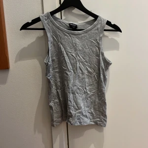 Grå linnetopp från Dollarstore - Säljer en enkel och stilren grå linnetopp från Dollarstore. Perfekt för varma dagar eller som ett lager under andra plagg. Toppen är ärmlös och gjord i ett mjukt material.