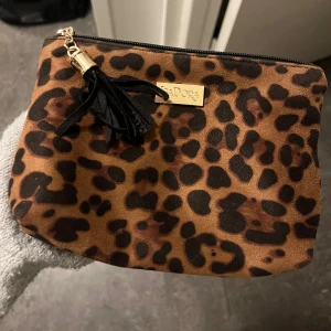 Leopardmönstrad necessär  - Snygg leopardmönstrad necessär från Isadora med dragkedja och en tofs. Perfekt för att ha smycken i eller andra små nödvändigheter.