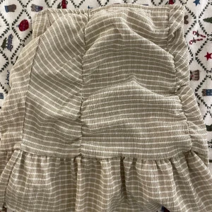 Beige rutig kjol från Gina Tricot - Säljer en söt beige rutig kjol från Gina Tricot i storlek XXS. Kjolen har volangdetaljer och en bekväm passform. Perfekt för en stilren look!