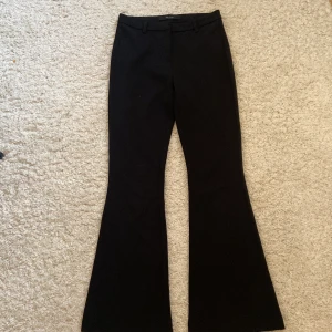 Svarta kostymbyxor från Vero Moda - Snygga svarta kostymbyxor från Vero Moda som är bootcut. Väldigt stilrena med knapp och en diskret dragkedja/ gylf. Använda ett fåtal gånger men är ändå i ett väldigt fint skick💕🤗