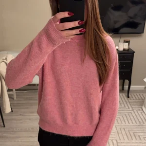 Rosa stickad tröja - Mysig rosa stickad tröja med långa ärmar. Perfekt för kyligare dagar då den värmer bra. Det är en hållbar tröja som ej nopprar då den bland annat består av nylon, alpacka och ull. 
